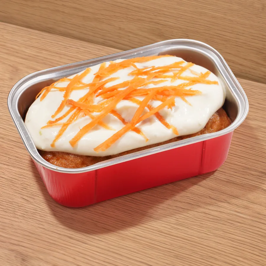 FOJO carrot cake in its tin, topped with frosting and grated carrot